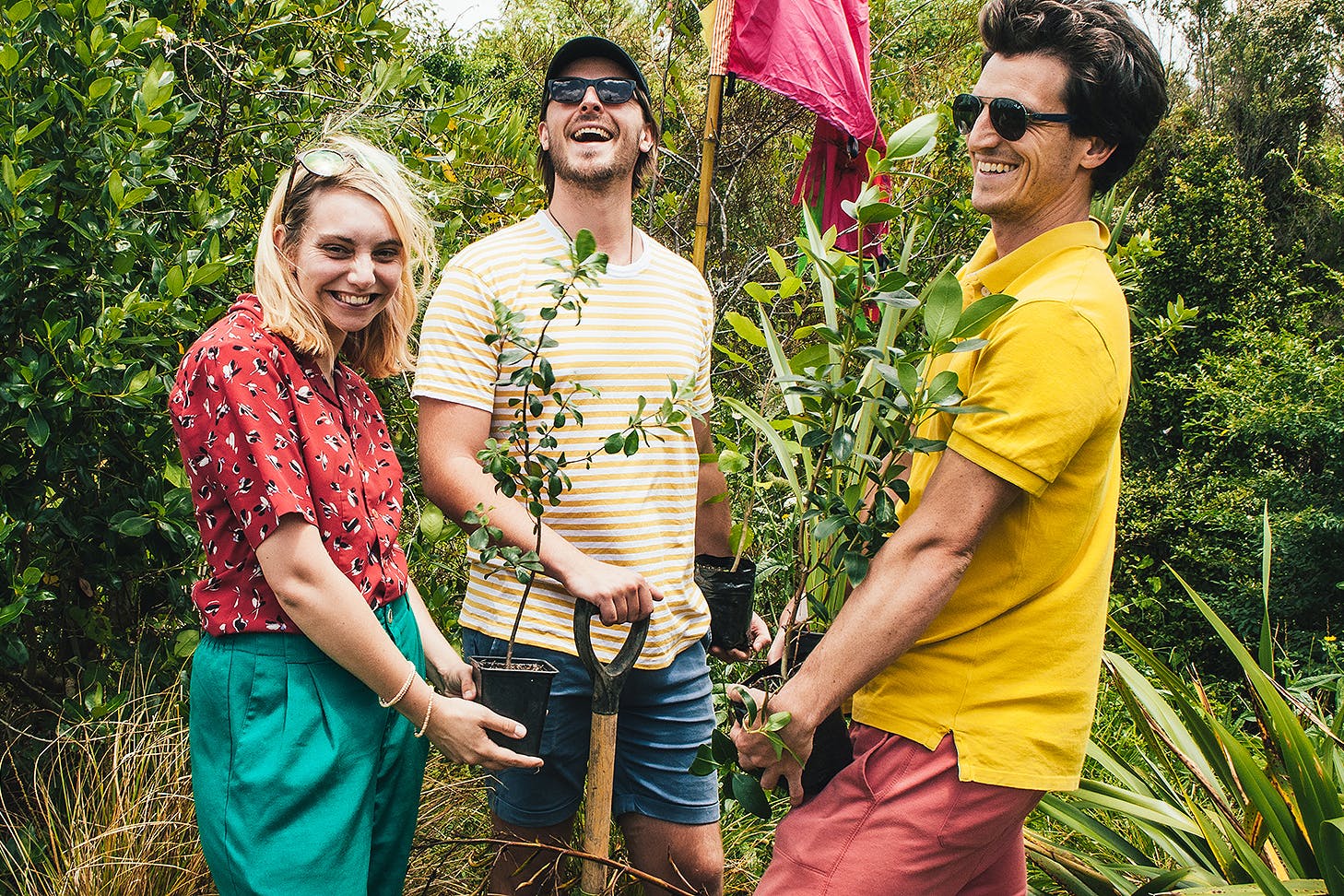 Three people have fun while planting trees.